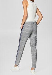 Grijze geruite broek met een smalle pasvorm, voorzien van blauwe strepen aan de zijkanten, zij- en achterzakken, en een gladde stoftextuur.