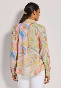 Langärmeliges Hemd aus leichtem Stoff mit einem mehrfarbigen Wirbelmuster in Pink, Gelb, Orange und Blau. Mit Knopfmanschetten und lockerem Schnitt.