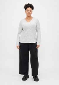 Suéter cinza canelado com decote em V, mangas longas, combinado com calças largas pretas e botas pretas robustas. Textura suave, corte descontraído.