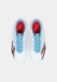 Le scarpe atletiche leggere presentano una tomaia in mesh bianca e blu, accenti rossi sulla soletta e un elemento di design nero sul lato.