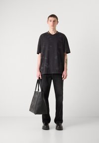 Svart oversized t-skjorte med subtil tekstur, svarte denimbukser og en elegant, svart skinn totebag med en fremtredende logo.
