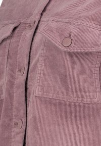 Sametová bunda v barvě popelavé růžové má vertikální pruhy, dvě náprsní kapsy a kulaté knoflíky na přední straně. Měkká textura a ležérní design.