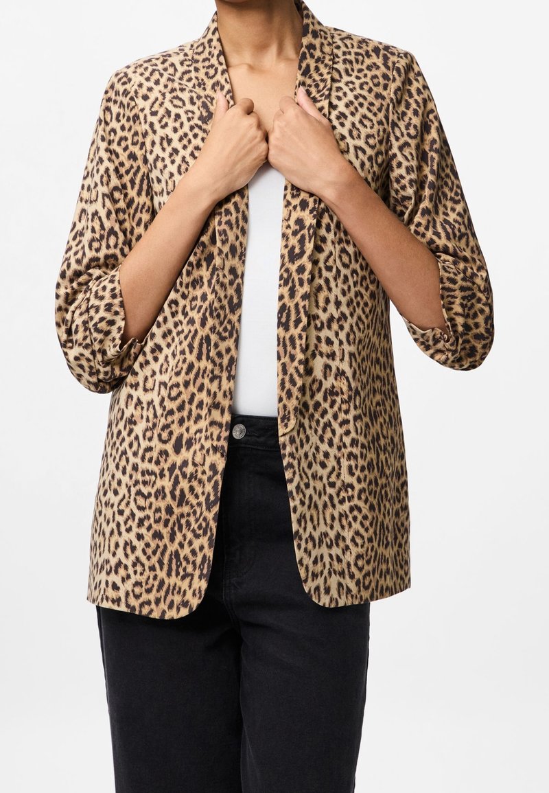 Leopardprintet blazer lavet af letvægtsstof; har åben front, 3/4-ærmer og en afslappet pasform. Stylet over en hvid top.