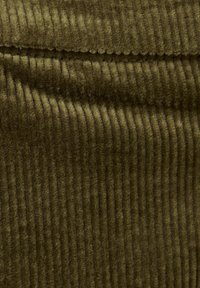 Olivgrüner Cordstoff mit vertikalen Rippungen, der eine weiche Textur und eine leicht flauschige Oberfläche aufweist, die die Tiefe des Materials betont.