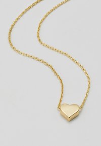Collier en cœur en or avec un pendentif lisse et une chaîne délicate avec des maillons ovales. Design simple mettant en valeur la forme du cœur.