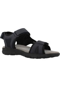 Sandalía negra ajustable con parte superior sintética, plantilla acolchonada y suela texturizada para un mejor agarre. Diseño de punta abierta con acentos de malla.
