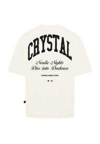 Přetáhnuté krémové tričko s černým textem "CRYSTAL" a grafikou. Další text zahrnuje "Nordic Nights Dive into Darkness" a malý tri-barvový akcent.
