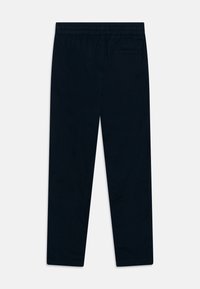 Tengerészkék nadrág elastikus derékkal, slim fit szabással és egy hátsó zsebből áll. Az anyag simának tűnik, egy enyhe textúrával.
