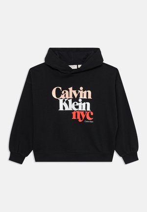 Svart kortärmad hoodie med ett framstående grafiskt logo i vitt, roséguld och röd text: "Calvin Klein NYC." Mjuk textil med ribbade muddar.