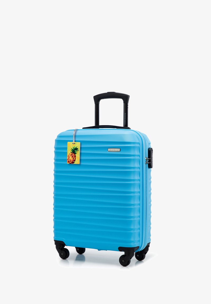 Harde koffer in felblauw. Kenmerken zijn textuur met verticale groeven, een uitschuifbare zwarte handgreep, draaiwielen en een ananasticker.