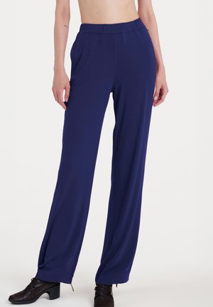 Pantaloni ampi di colore blu navy realizzati in tessuto morbido e elasticizzato; presentano una vita elastica e una superficie liscia con tasche laterali.
