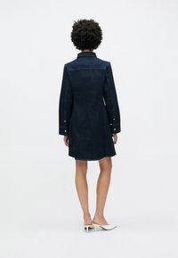 Τζιν φόρεμα σε σκούρο μπλε, με γιακά και μακριά μανίκια, με εφαρμοστή μέση και φουσκωτή φούστα, φινιρισμένο με λεπτομέρειες κουμπιών.