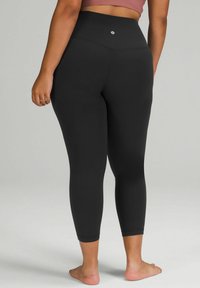 Crne legging hlače visokog struka s glatkom teksturom, skrojene do sredine lista, s malim logotipom iznad struka. Prilagodljiv kroj.