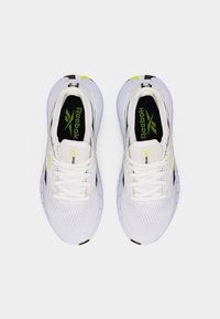 Ζευγάρι λευκών αθλητικών παπουτσιών Reebok με μαύρες και νέον κίτρινες λεπτομέρειες, απεικονισμένα από πάνω σε απλό φόντο.