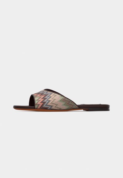 Sandale plate à glissière avec dessus en tissage multicolore en zigzag et semelle ainsi que bordure marron sur fond blanc.