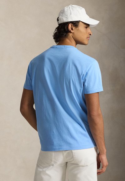 Ανοιχτό μπλε βαμβακερό t-shirt με κοντά μανίκια, άνετη εφαρμογή, στρογγυλή λαιμόκοψη και λεία υφή, συνδυασμένο με λευκό μπέιζμπολ καπέλο.