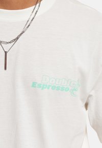 Weißes Baumwoll-T-Shirt mit einem mintgrünen Drucklogo "Double Espresso" auf der linken Brustseite; glatte Textur, normale Passform.