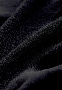 Czarna tkanina o teksturowanym splocie, prezentująca gładkie i nieregularne powierzchnie, podkreślająca swoją miękką i elastyczną naturę.