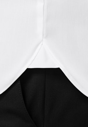 Witte stof met een gladde textuur, met een afgeronde zoom, overlapt een zwarte stof met een gestructureerde afwerking. Naaddetails zijn zichtbaar.