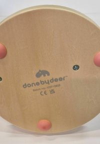 Base redonda de madera con tres patas de goma rosa, tornillos y el logo "done by deer" con número de lote y marcas de certificación.