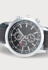 Orologio cronografo con quadrante nero, lancette argentate e tachimetro. Presenta sottodial rossi e bianchi, cassa in argento e cinturino scuro texturizzato.