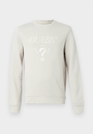 Felpa grigia chiara con collo a giro, polsini e orlo a coste. Presenta un logo "GUESS" in rilievo bianco e un design a punto interrogativo sul davanti.