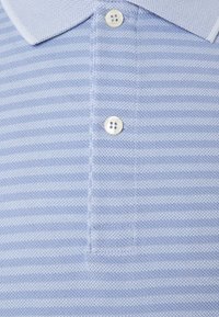 Light blue polo shirt featuring a textured knit with horizontal white stripes, a collar, and three white button closures.