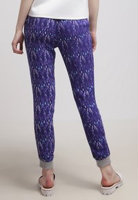 Lila joggers med ett diamantmönster i blått och vitt, elastiska mudd, och en mjuk midja, designade för komfort och rörlighet.