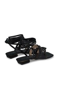 Sandalias negras con tacón plano, que presentan un intrincado detalle de cuentas y tiras cruzadas. Están hechas de materiales sintéticos con una textura suave.