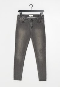 Harmaat farkku skinny-farkut, joissa on hieman haalistunut pinta, viisi taskua ja perinteinen nappi- ja vetoketjukiinnitys. Roikkuu mustasta koukusta.