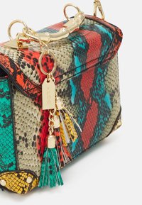 Torebka z nadrukiem w wielokolorowe wzory węża, ze złotymi elementami, wyposażona w uchwyt w stylu bambusa i kolorowe frędzle. Teksturowana powierzchnia i usztywniony kształt.