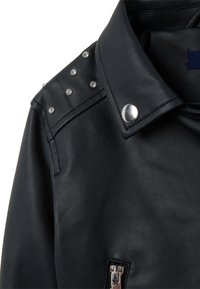 Veste en cuir noir avec un col structuré, des clous argentés sur les épaules et une fermeture éclair métallique. Fini doux et texturé.