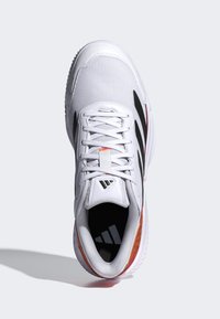 Witte sportschoen met mesh bovenwerk, zwarte zijstrepen en een gestructureerde zool. Voorzien van vetersluiting en merklogo op de tong en binnenzool.