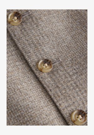 Hnedá textúrovaná tkanina s dvoma veľkými priehľadnými gombíkmi obsahujúcimi jemný vzor a kontrastné detaily zo šitia.