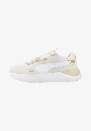 Zapatillas deportivas blancas y beige con texturas de malla y ante, que cuentan con una suela blanca gruesa y un sutil logo en el lado.