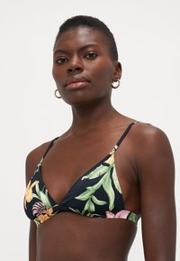 Kvetinový bikiny top na čiernom pozadí, s zelenými listami a ružovo-oranžovými kvetmi. Má tenké nastaviteľné ramienka a trojuholníkový tvar.