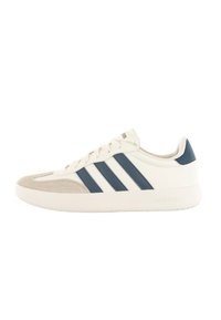 White sneaker with navy blue stripes, suede toe cap, and textured accents. Features a rubber sole and flat laces for closure.