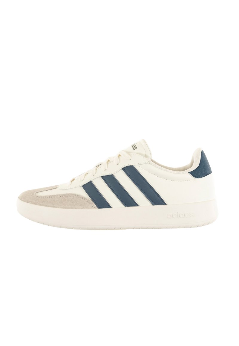 White sneaker with navy blue stripes, suede toe cap, and textured accents. Features a rubber sole and flat laces for closure.