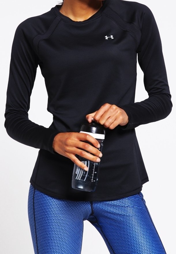 Svart långärmad träningsskjorta med rundad halsringning och sömdetaljer, tillsammans med blå mönstrade leggings. Håller i en genomskinlig vattenflaska.