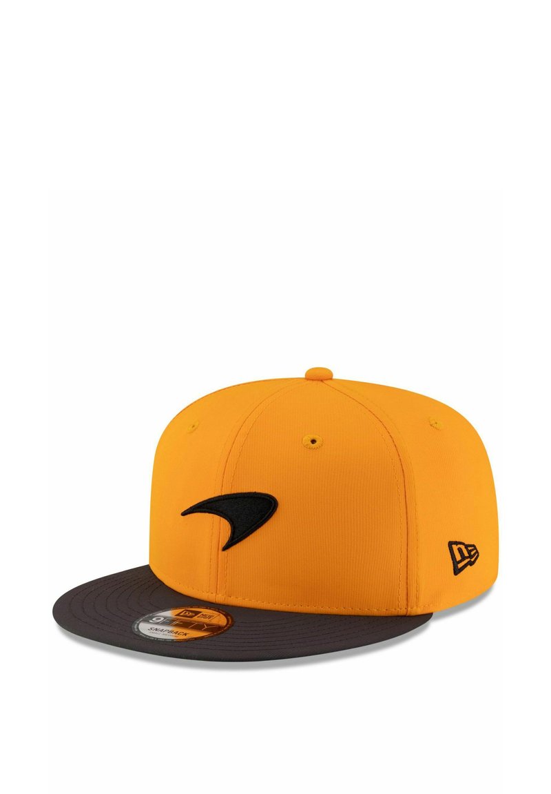 Gelbe Kappe mit einem schwarzen Logo auf der Vorderseite, einem dunkelgrauen Schirm und einem strukturierten Stoff. Enthält einen runden Größenaufkleber auf dem Schirm.