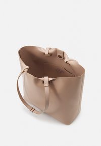 Beige leather tote bag with a soft texture, two straps, and a spacious interior. Features a central divider and subtle branding inside.