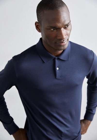 Ναυτικό τζιν πουκάμισο μακρυμάνικο με γιακά, δύο κουμπιά και εφαρμοστό σχέδιο, φτιαγμένο από λείο ύφασμα, με ελάχιστες ραφές.