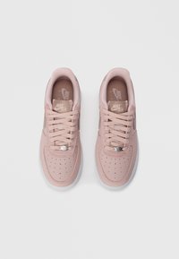 Sapatilhas Nike Air rosas com tecido texturizado, caixa dos dedos perfurada e sapatilhas planas. Apresentam um detalhe do logótipo em prata e solas de borracha brancas.