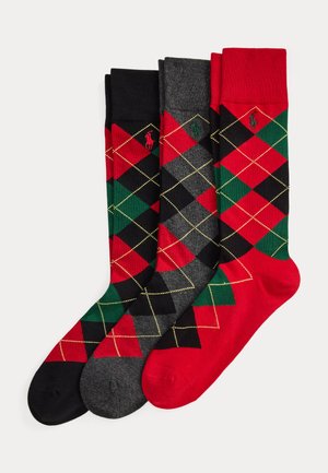 Trois paires de chaussettes à motif losanges sur bases noire, gris foncé et rouge avec des losanges rouges, verts et noirs et de petits logos brodés.