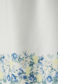 Blomster mønster stoff med blå, gule og grønne blomster på hvit bakgrunn, med en glatt tekstur og myk fall.