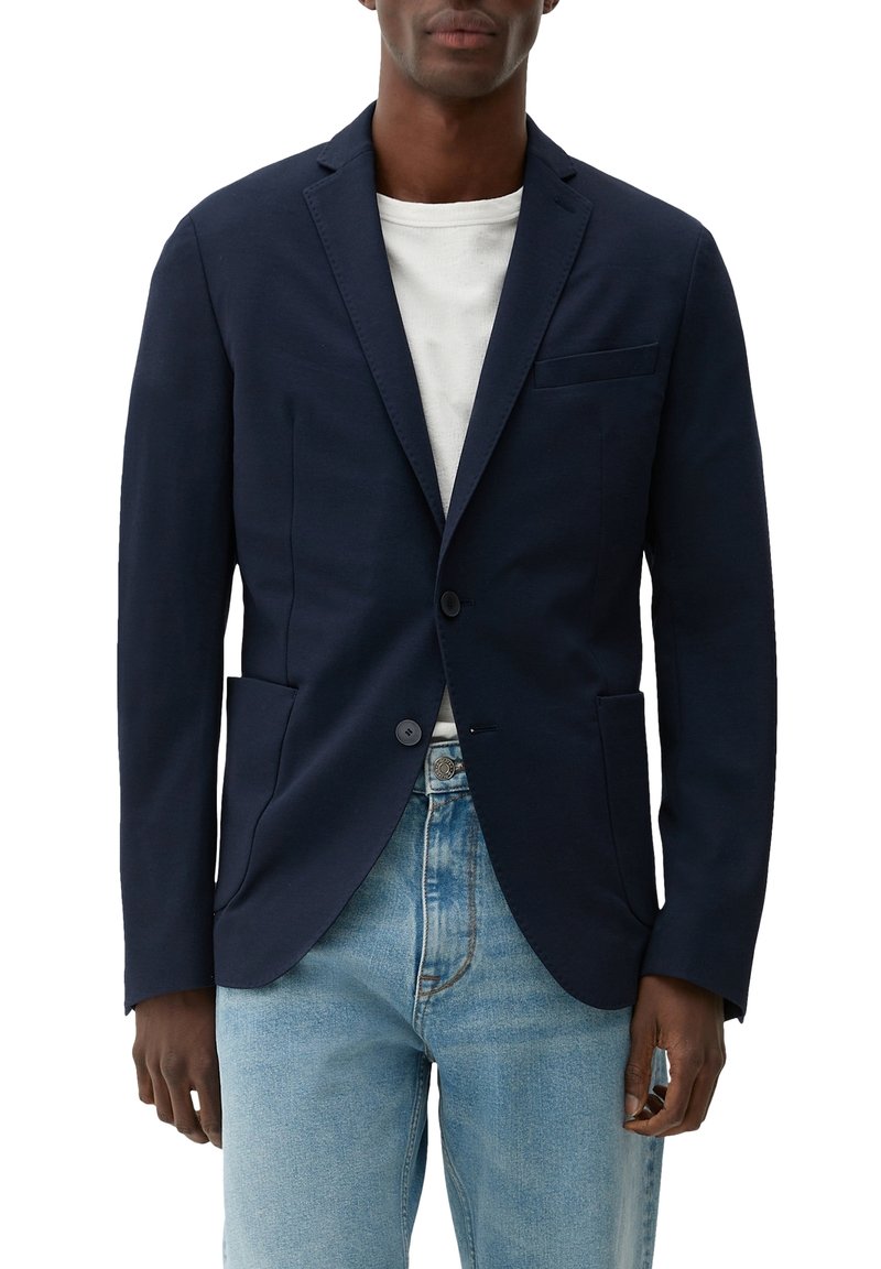 Marineblazer aus einem strukturierten Stoff, mit einer Einzelknopfverschlusst, zwei vorderen Taschen und einer Brusttasche, über einem weißen T-Shirt.