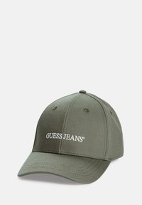 Olijfgroene honkbalpet met "GUESS JEANS" geborduurd in het wit aan de voorkant, voorzien van gestikte panelen en ventilatieopeningetjes.