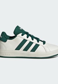 White athletic shoe with three dark green stripes, textured outsole, round toe, and contrasting laces. Features logo on tongue and heel.