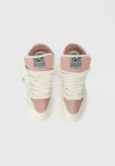 Sneakers albe de tip high-top cu accente roz deschis, cutie perforată pentru degete, șireturi plate și un logo proeminent pe limbă. Interior texturat.