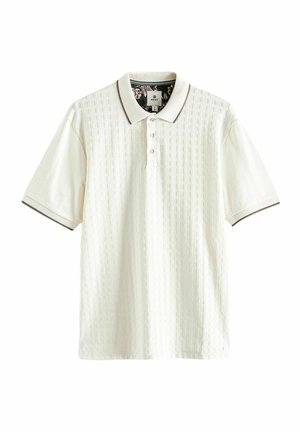 Polo blanc avec motif en quadrillage texturé, manches courtes et patte de boutonnage à trois boutons. Présente une bordure contrastante au niveau du col.
